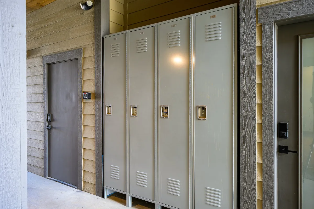 A practical locker area with metal lockers and a brown door, designed for storing personal items or changing before and after outdoor activities. The space is utilitarian, emphasizing functionality and after-sport camaraderie.