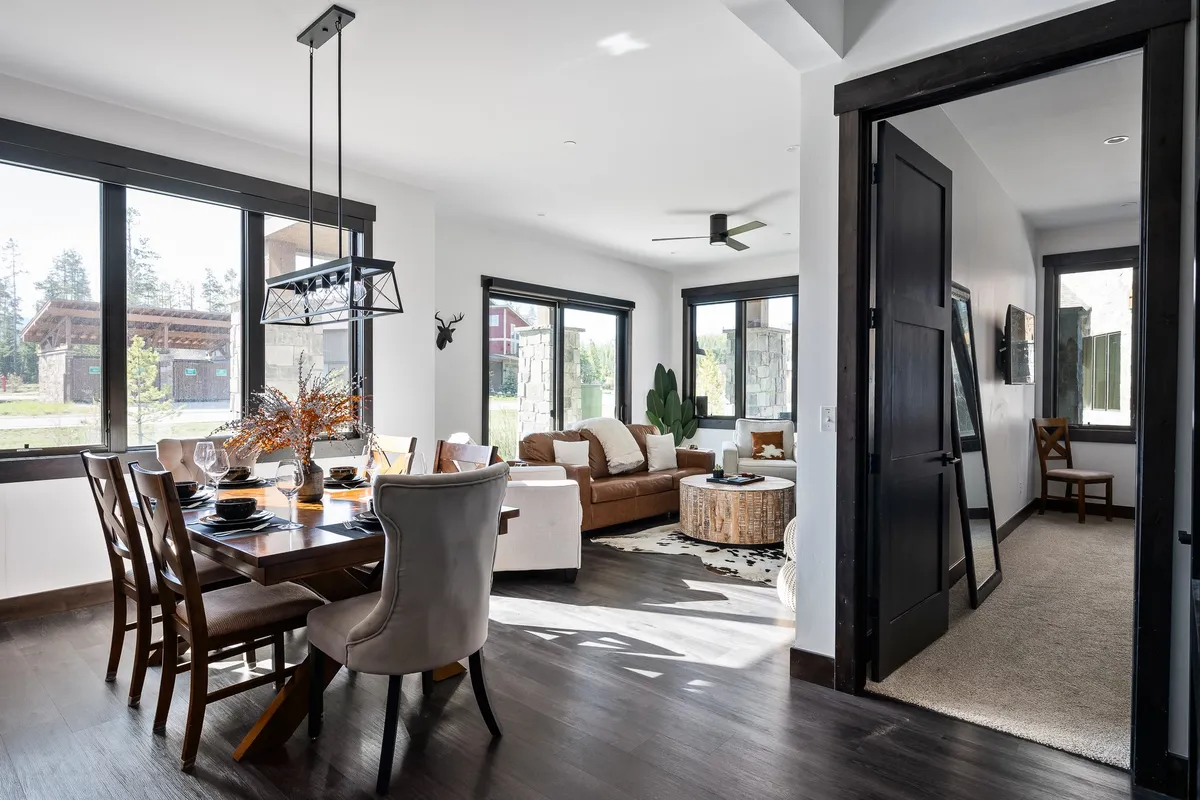 A welcoming, open-plan living and dining area with a dining table and chairs set near large windows, alongside a cozy sofa set and coffee table. The natural light fills the space, highlighting its suitability for group dining, holiday celebrations, and casual gatherings.
