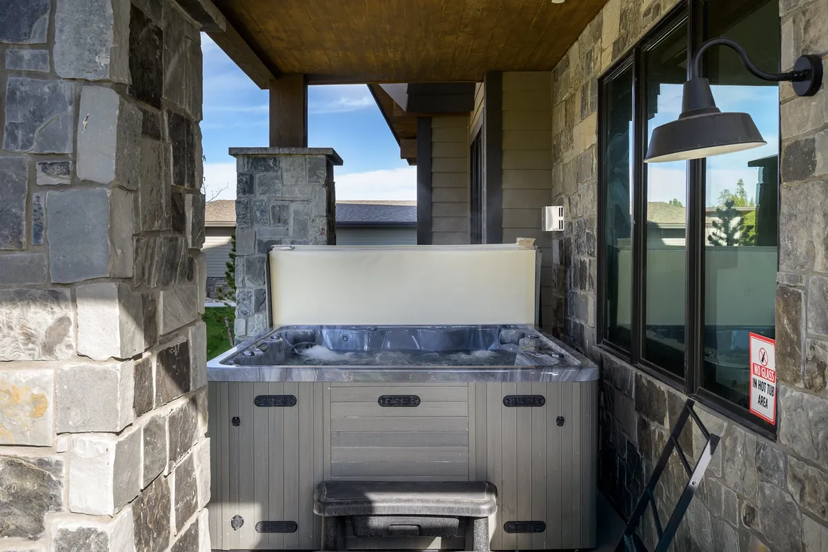 This exterior image showcases a private hot tub nestled beside charming stone pillars and under warm outdoor lighting. The setting is tranquil, ideal for relaxing evenings under the stars or a morning soak with coffee in hand. The hot tub is the focal point, with inviting surroundings that hint at privacy and comfort.